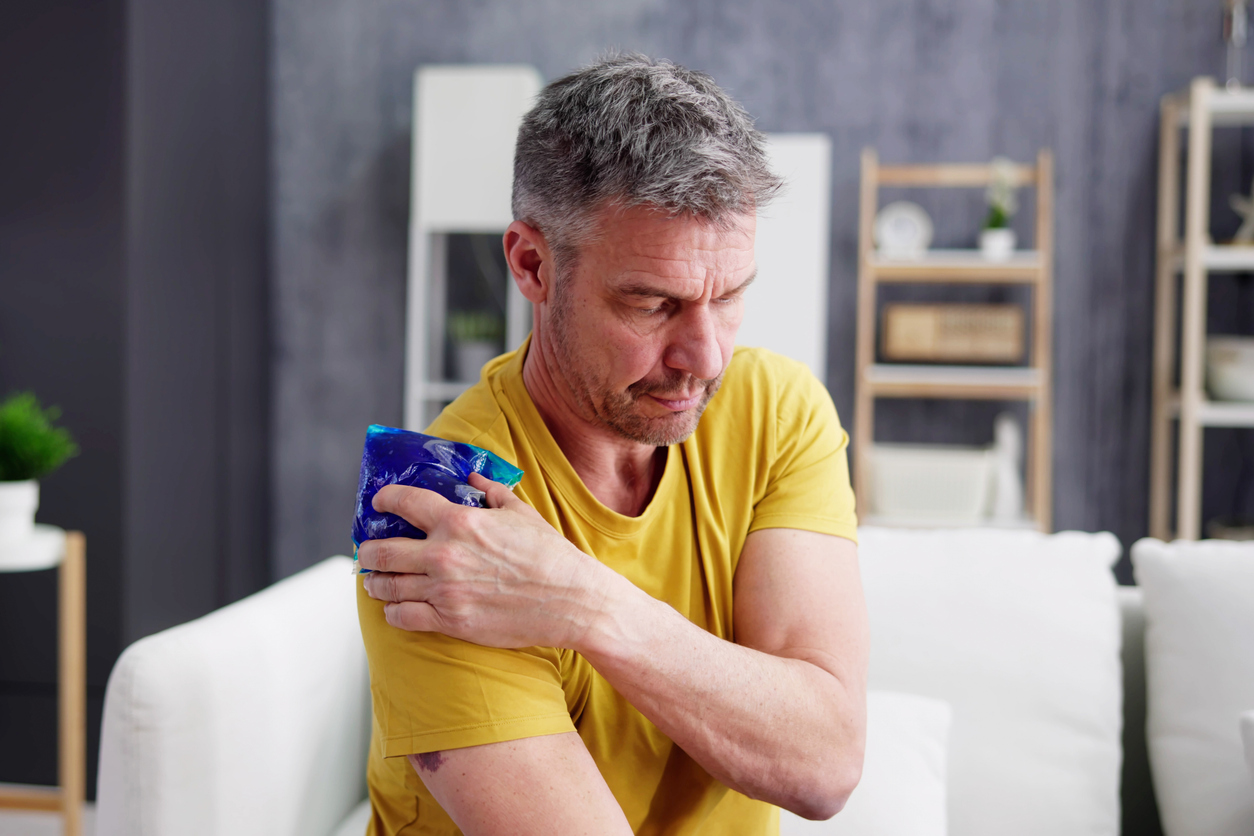 A man using a cold compress on his should to help heal an injury.